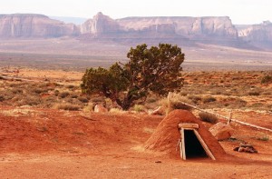 MONUMENT VALLEY, ARIZONA - A Navajo sweat lodge near Monument Valley Navajo Tribal Park looks deserted with the majestic red sandstone cliffs of Horse Canyon in the background.  The sweat lodge is "the Navajo answer to the sauna," according to San Juan County tourism officer Malva Jones, and "is excavated with a mounded dirt front supported by bent branches from the Tamarisk woven into an arch and finished with a wood-framed door."  A  ring of board seats surrounds a large pit which holds volcanic and river rocks which have been heated outside in a fire pit.  "Then the doorway is closed off by a heavy blanket or large [animal] hide," Jones said, "and water is poured on the rocks, creating copious amounts of steam.  The younger men use this as a sauna more and more often, but the older men only use the lodge for special ceremonies.  Women are not allowed."  The Navajo reservation covers over 27,000 square miles, slightly larger than the state of West Virginia, yet it has barely 11 percent of West Virginia's 18,000 miles of paved roads.  Most of this section of the northern reservation is extremely isolated, with trips to town for groceries or shopping taking the better part of a day.  "I love nature and have great respect for it," Reppert says.  "The Navajo people are very spiritual--they commune with nature and with the Creator, and in that way I feel connected.  My real life is in my writing and my photography and in a sense my spiritual life.  The reservation is now a part of me, a part of who I am."  (Betty E. Cauler/TMC)  for Adventures story.